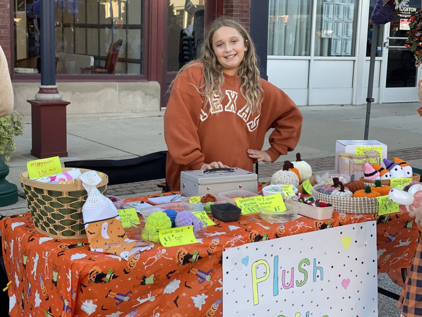 Girl posing and smiling standing behind vendor booth table