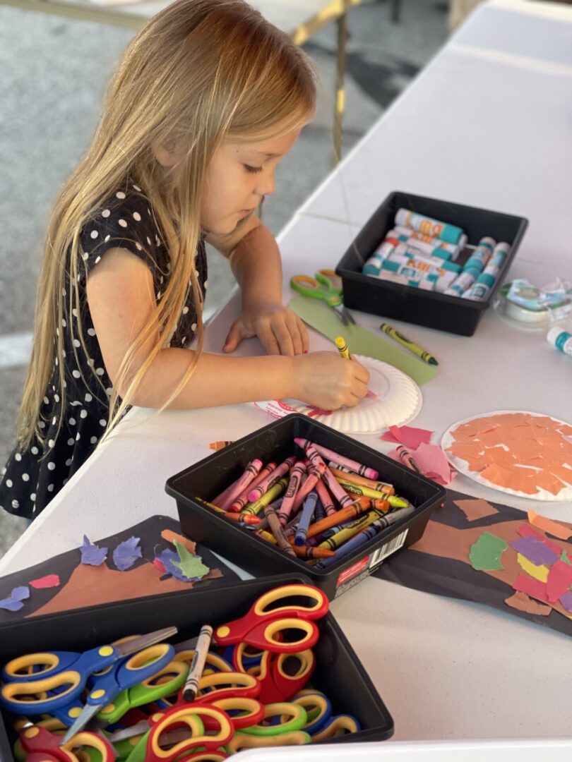 Little coloring a pumpkin with crayons at Columbia City Connect's First Fridays