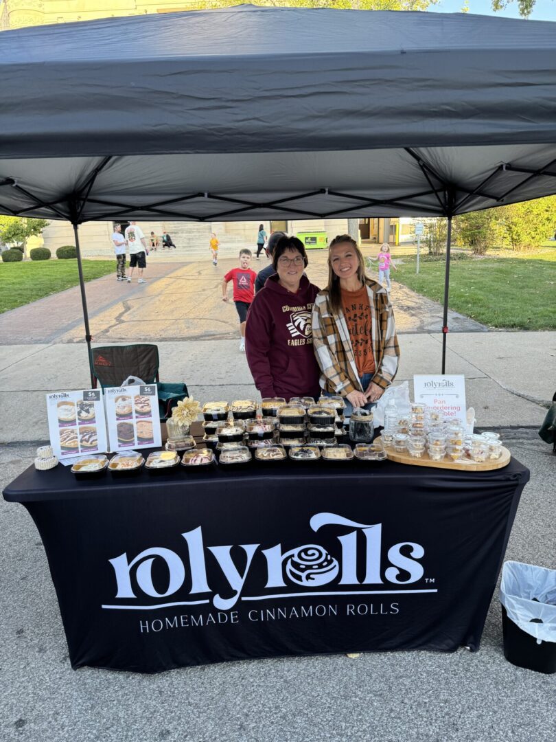 Two people smiling under their food vendor booth at Columbia City Connect's First Fridays