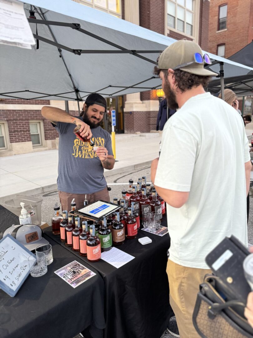 Vendor pouring drink for customer at Columbia City Connect's First Friday event