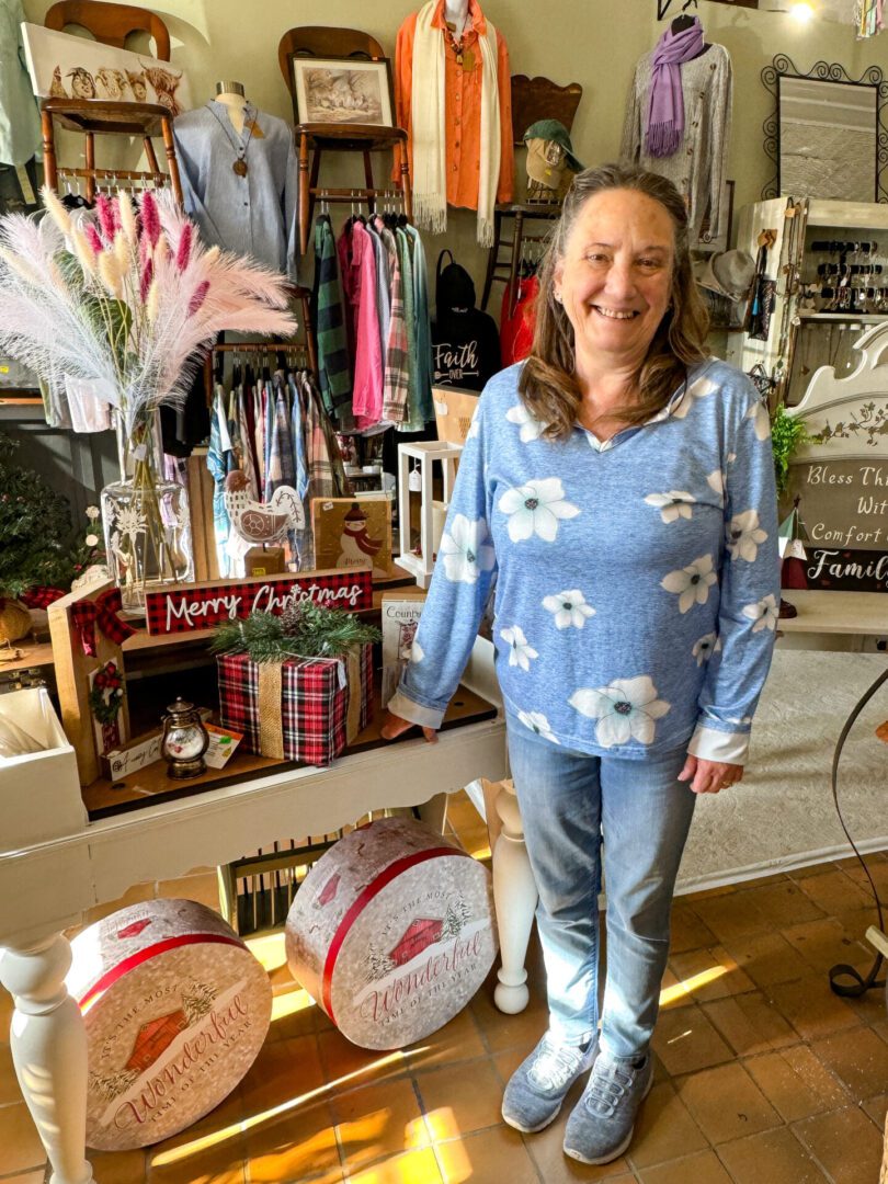 Owner of The Junction Cafe and Home Decor poses for picture in front of store display