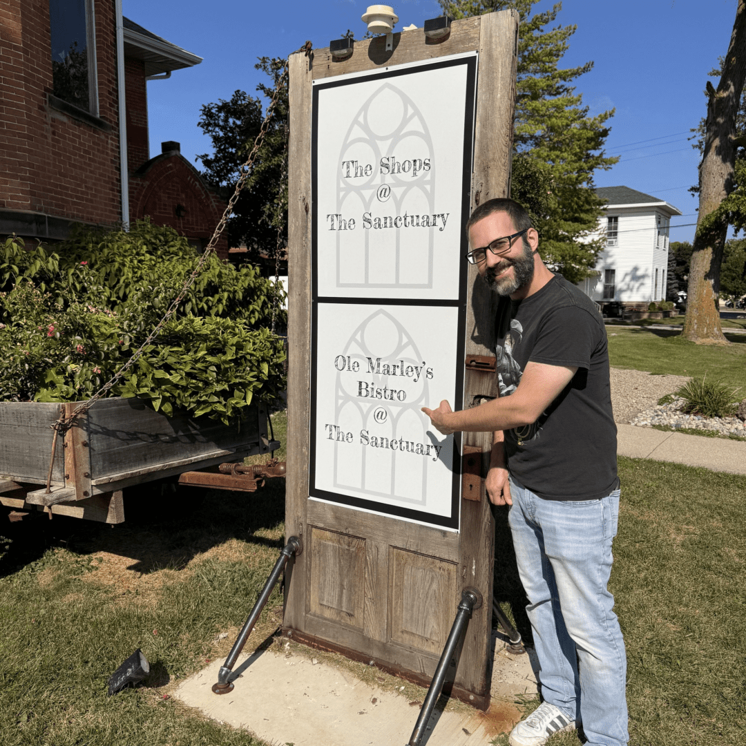 Aaron pointing to a sign of his restaurant in Columbia City