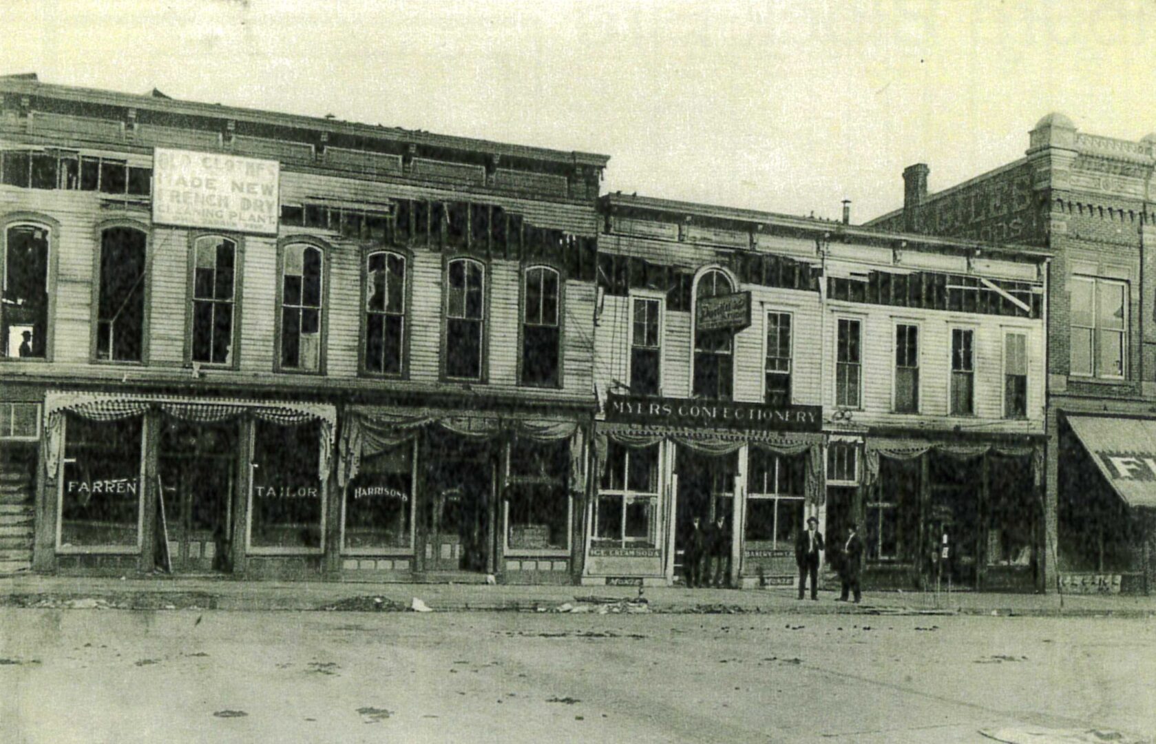 Washburn Block aftermath of the fire.  Farren's Tailor sign still hangs in from to the store.  Myers Confectionery sign hangs above a charred entrance as the Pontius Studio sign hangs over the second floor.  Notice Flox's Department Store canopy on the right of the photograph.