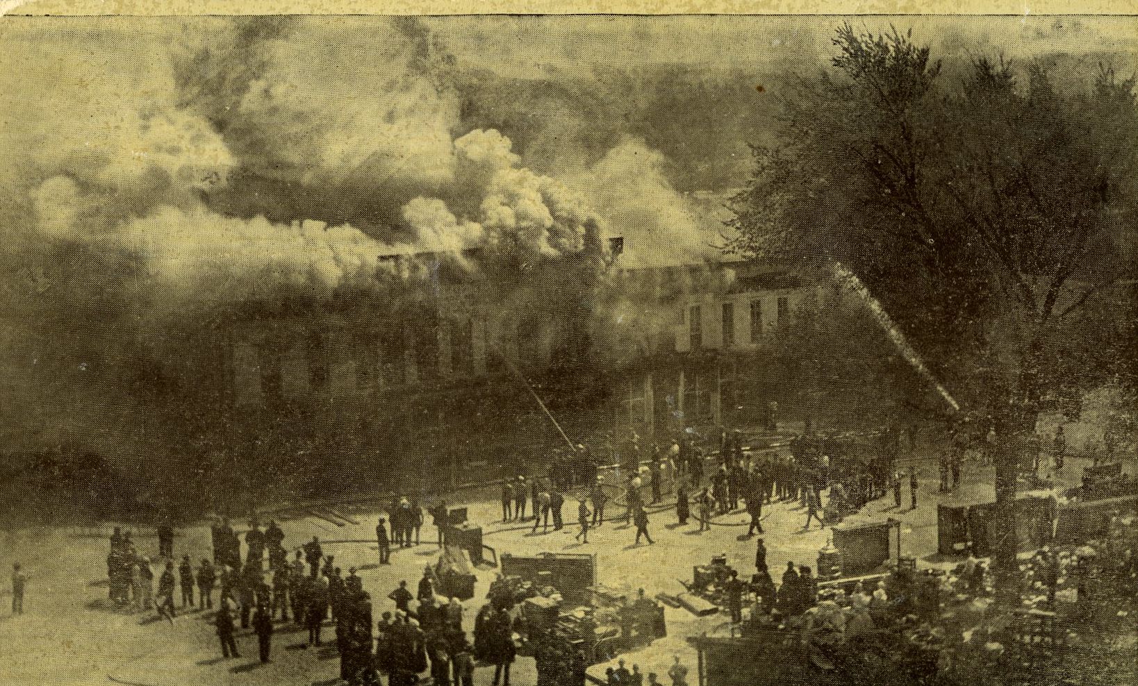 Firefighters try desperately to keep the fire at bay. Notice all of the items in the street that were saved from destruction.